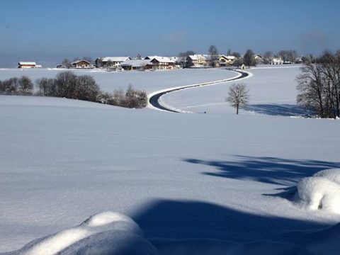 Снежное поле и деревня вдалеке зимой